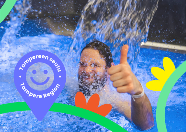 A man stands under a waterfall in a swimming hall or spa, smiling and giving a thumbs-up. Colourful graphic elements like flowers and arches decorate the foreground. In the bottom left corner, there’s a blue-violet map pin with a smiley face and the text ‘Tampereen seutu • Tampere Region’.